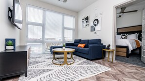 A modern living room with a sofa, coffee table, and a TV mounted on the wall. - Yugo Guest Suites (Urbana)