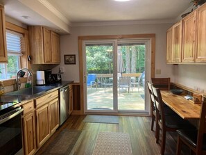 A kitchen with wooden cabinets, a dishwasher, a sink, and a dining area with a table and chairs.