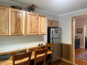 Una cocina con armarios de madera, un refrigerador y una mesa de comedor con sillas.