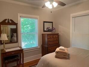 A bedroom with a bed, a dresser, a nightstand, a mirror, and a window with blinds.