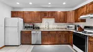 A modern kitchen with wooden cabinets, stainless steel appliances, a dishwasher, and a granite countertop.