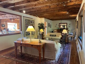 Ein gemütliches Wohnzimmer mit Holzbalkendecke, einem Essbereich mit Stühlen und Tisch sowie einem Sofa mit Kissen mit der Aufschrift 'Gone Fishing'.