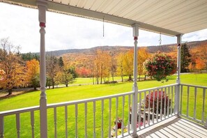 A covered porch with a view of a green lawn and autumn-colored trees. - Escape to Serenity: 18-Acre Catskill Retreat (Margaretville)