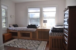 Un dormitorio con cama, lámpara, cómoda y ventana.