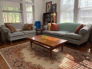 Ein Wohnzimmer mit einer gepolsterten Couchgarnitur in Rautenmuster, einem Holztisch und einem Teppich mit Muster.