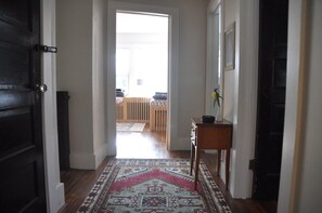 A hallway with a patterned rug, a wooden bench, and a small table with a vase. - Private Hot Tub - 3 bedroom Village Home (Fleischmanns)