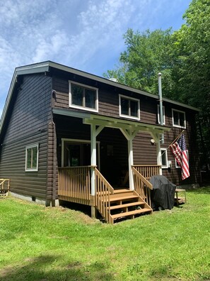 A two-story wooden house with a porch and a flag.
