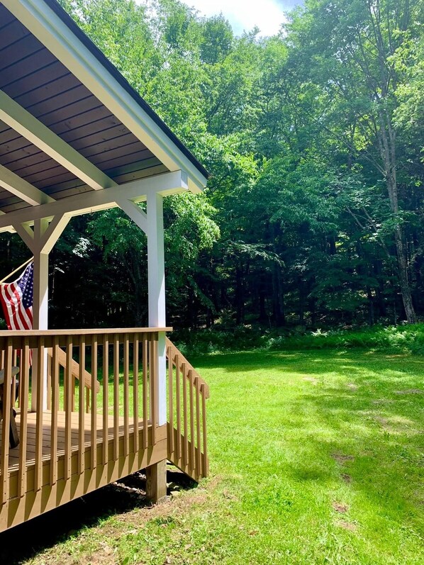 A wooden deck with a railing, a flag, and a covered area with a roof.