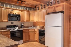 A kitchen with wooden cabinets, a microwave, a stove, a dishwasher, and a refrigerator. - Cabin in the Heart of the Catskills (Arkville)