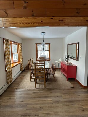 A dining area with a wooden table and chairs, a red cabinet, and a large mirror on the wall. - Cozy, Spacious Cabin with Kid-Friendly Amenities (Roxbury)
