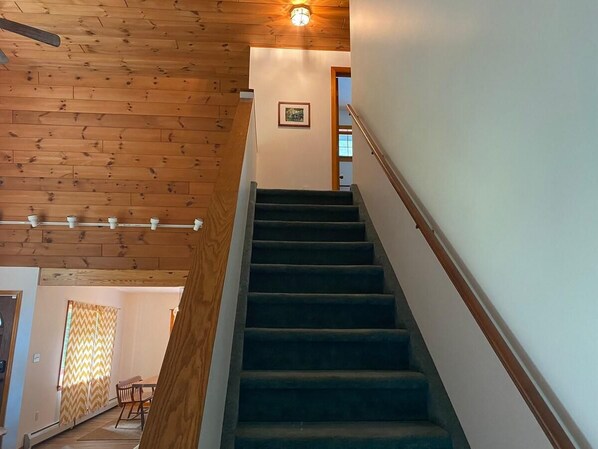 Una escalera de madera con barandilla que lleva a un piso superior.