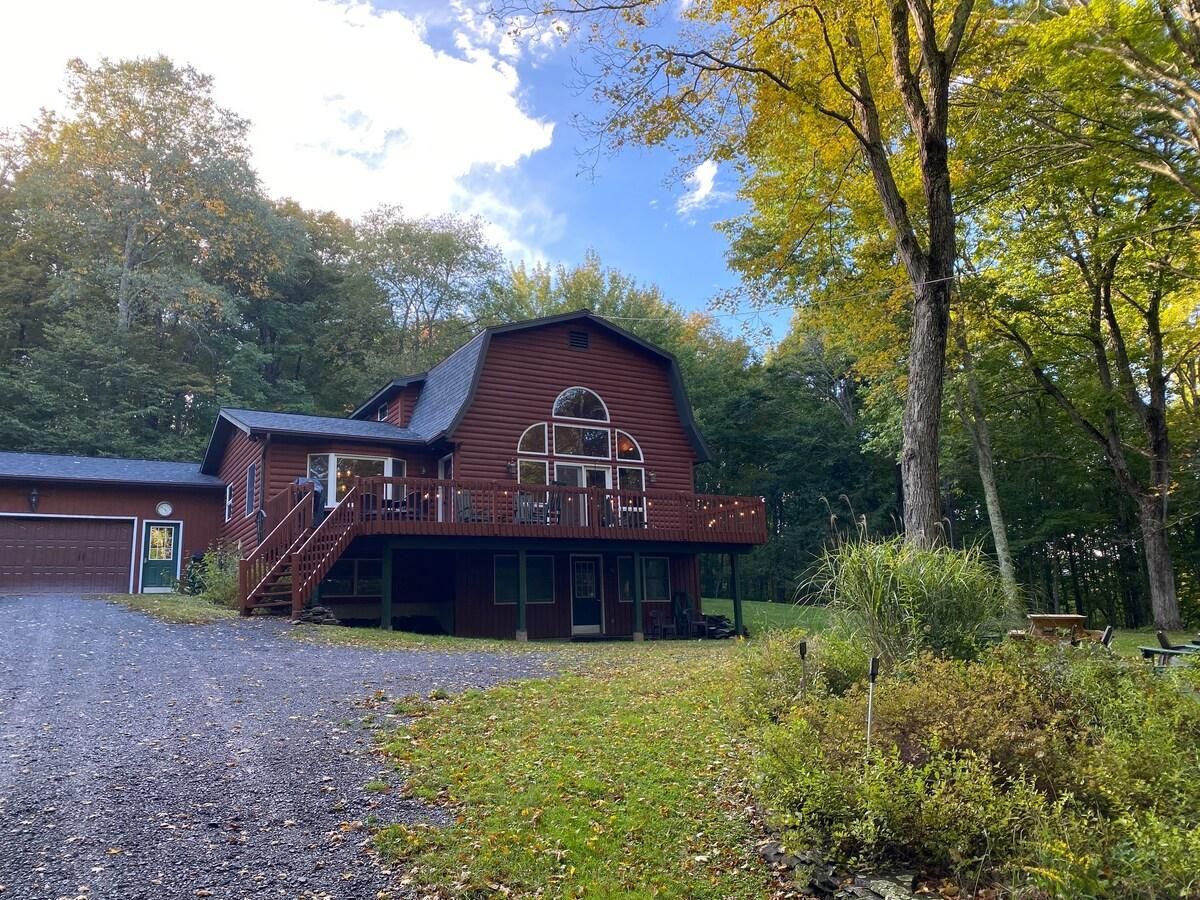 A wooden barn-style building with a porch and a staircase leading to a deck.