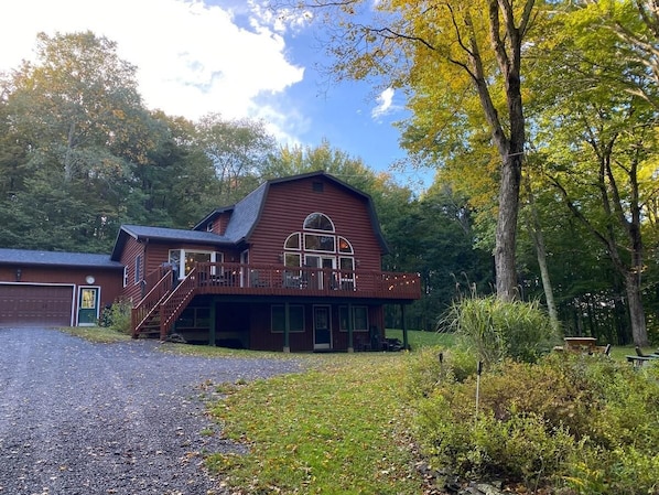 A wooden barn-style building with a porch and a staircase leading to a deck.