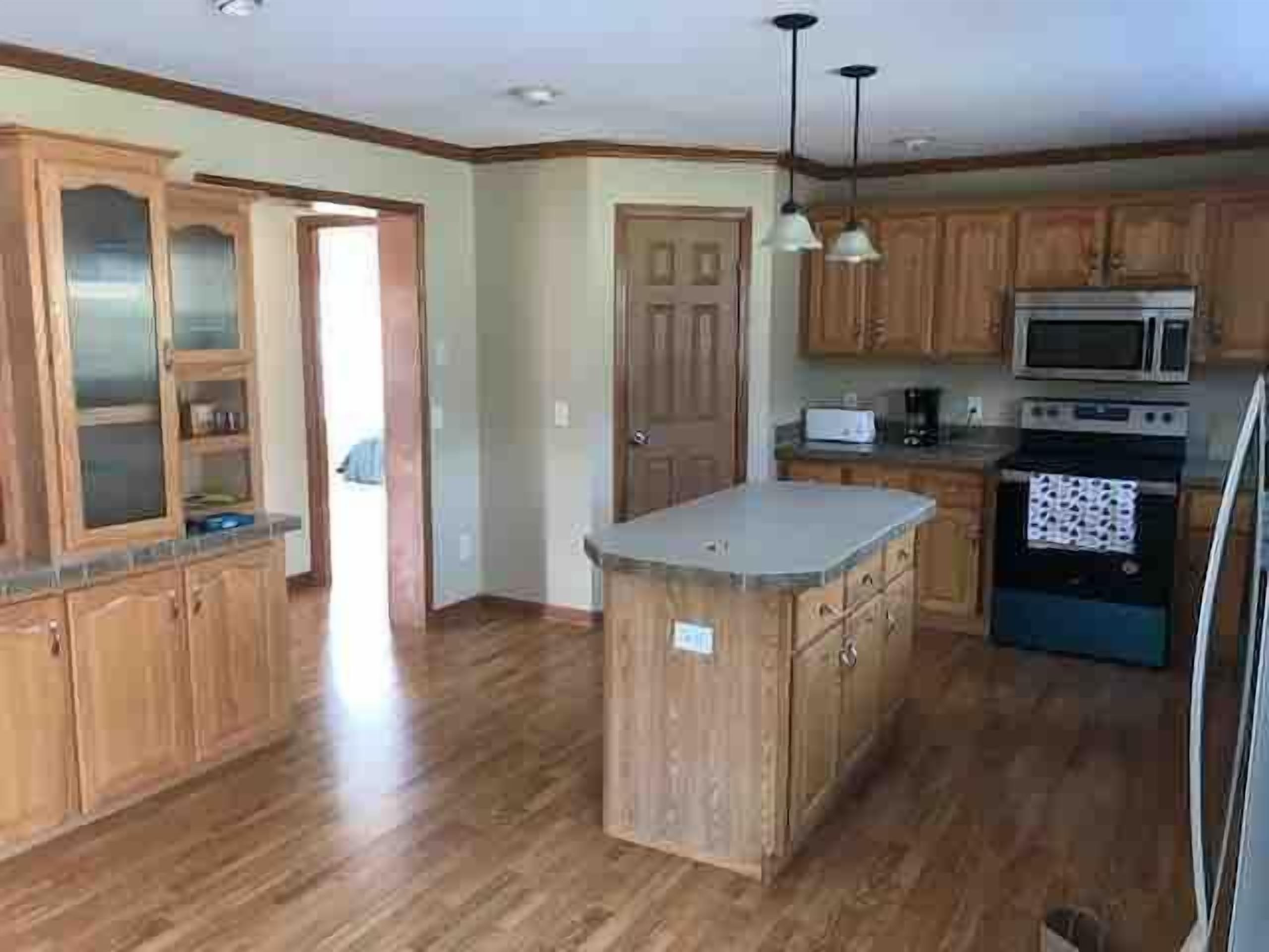 A kitchen with wooden cabinets, a central island, a microwave, and a stove.