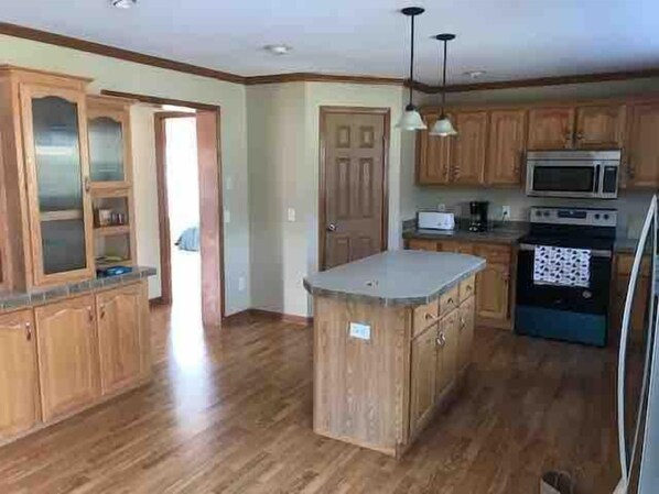 A kitchen with wooden cabinets, a central island, a microwave, and a stove.