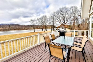 A deck with a table and chairs, overlooking a river and trees.