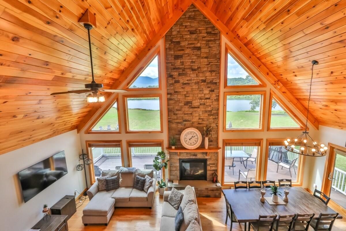 Un loft espacioso con techo alto, chimenea de piedra, zona de comedor y ventanas grandes que ofrecen vistas al exterior.