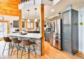 Une cuisine moderne dotée d’un îlot central, d’appareils électroménagers en acier inoxydable et d’éléments décoratifs en bois.
