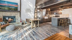 Een moderne keuken met een stenen openhaard, een houten eethoek en uitzicht op het landschap.