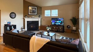 Un salon avec une cheminée, un téléviseur, un canapé et une table basse.
