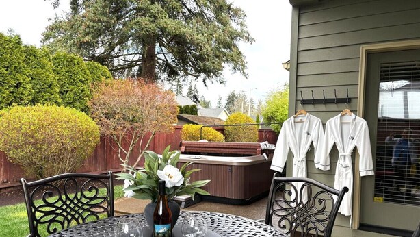 Une terrasse extérieure avec une table ronde, des chaises et un jacuzzi.