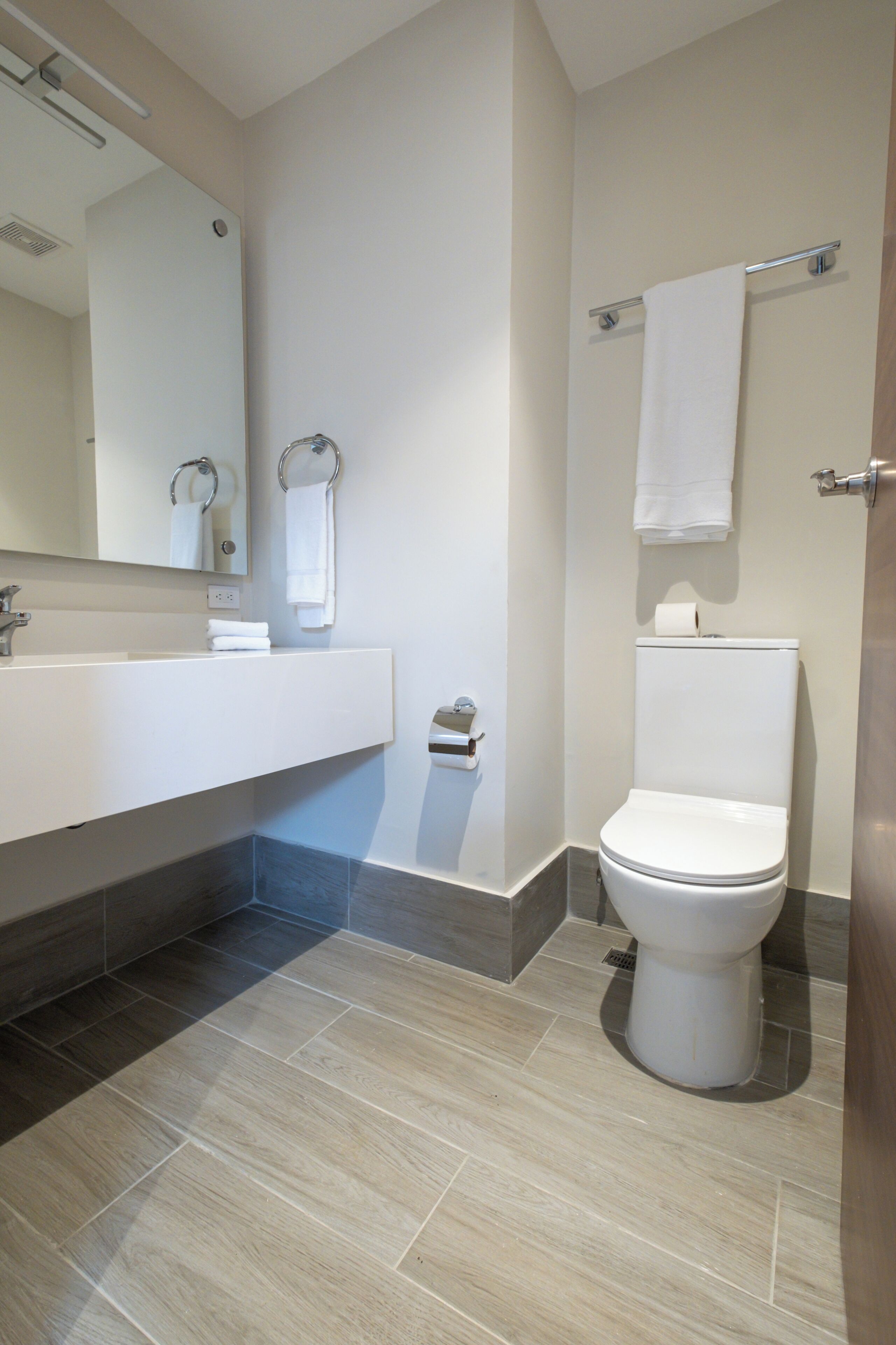 A modern bathroom with a white sink, mirror, and toilet.