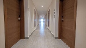 A long, narrow hallway with wooden doors on both sides and a light-colored tiled floor.