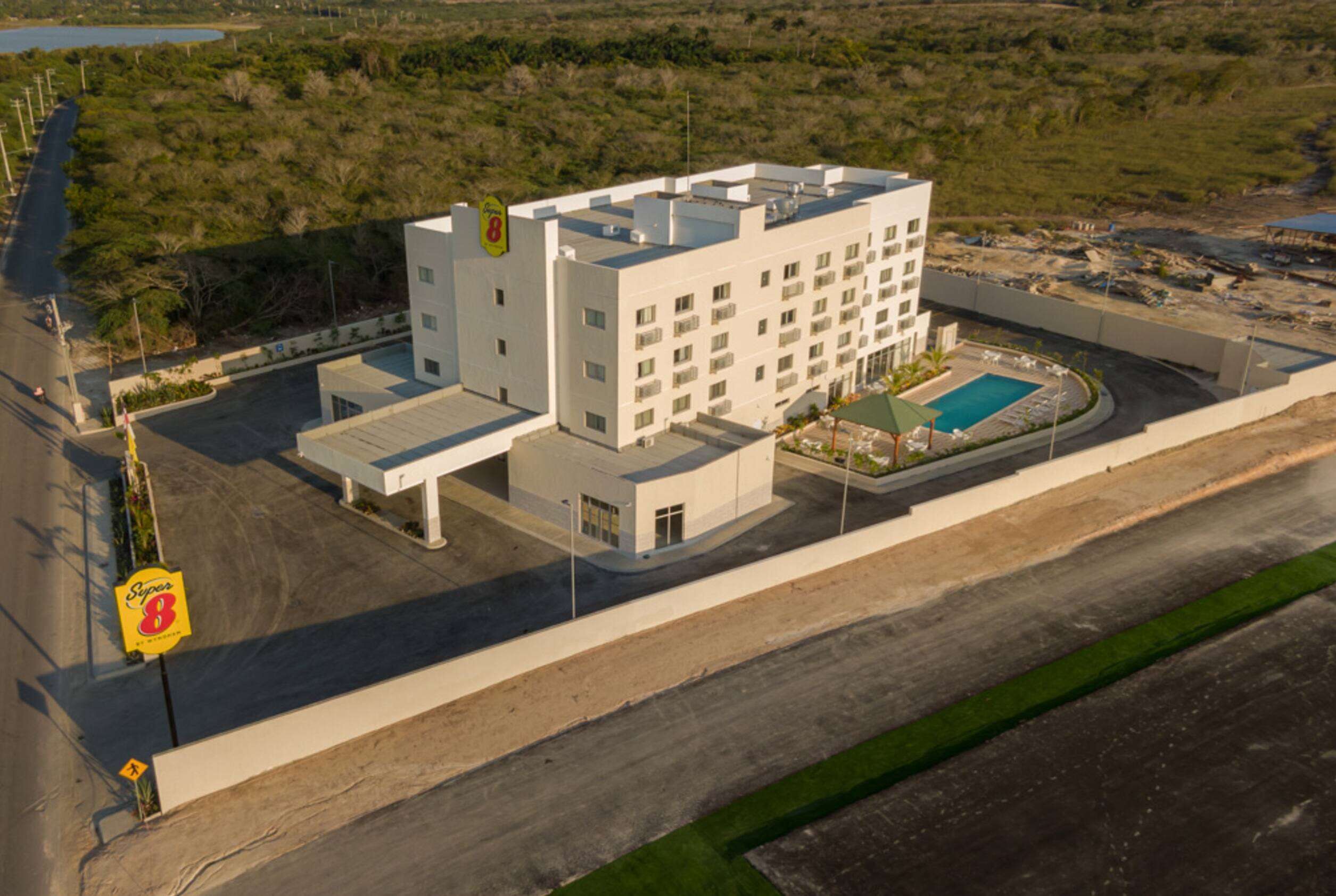 Un hotel moderno con piscina, parcheggio e un cartello che indica una stazione di servizio nelle vicinanze.