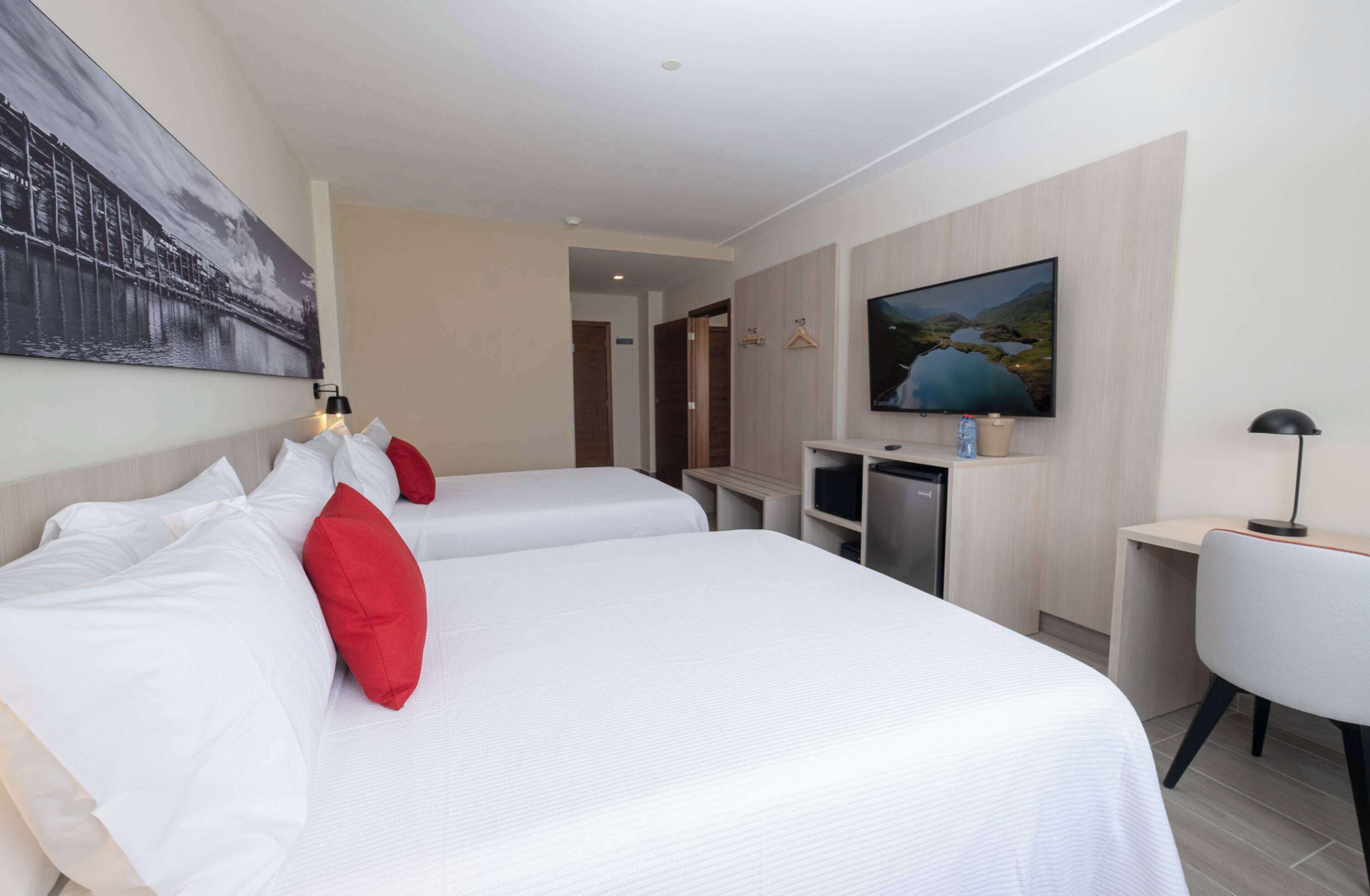 A hotel room with two beds, a TV, a desk, and a chair.
