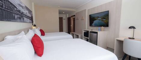 A hotel room with two beds, a TV, a desk, and a chair.