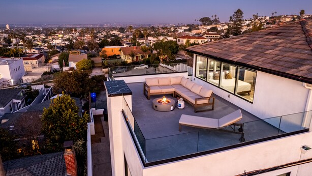 A rooftop terrace with a fire pit, outdoor seating, and a city view.