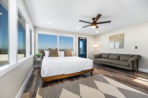 A bedroom with a large bed, a ceiling fan, a sofa, and a view of the outdoors. - Newly Remodeled Mansion With Breathtaking 300° Views! AC, Parking, Spacious! (San Diego)
