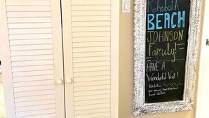 A white cabinet with a decorative shell and starfish arrangement on top. A chalkboard sign on the wall reads "Welcome to Rehoboth Beach Johnson Family" with a message for visitors. - Family Paradise • Hot Tub + EV Charger • 4 BR/3 BA (Rehoboth Beach)