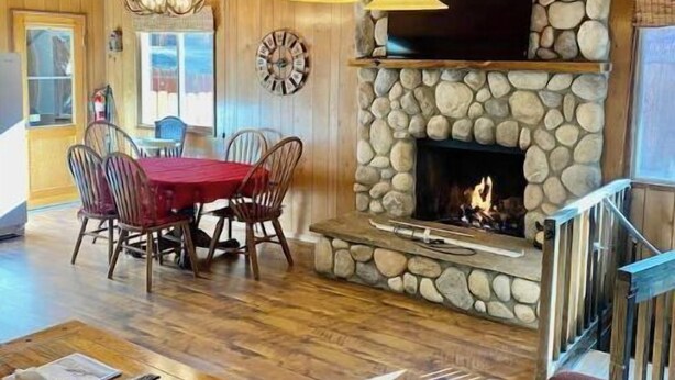 Un intérieur chaleureux avec une cheminée en pierre, une table à manger en bois et un coin salon confortable.