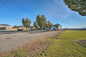 Una calle residencial con casas, un área verde y cielo despejado.
