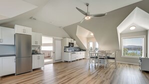Uma cozinha ampla com design moderno, com armários brancos, uma geladeira de aço inoxidável e um espaço de refeições com mesa e cadeiras.