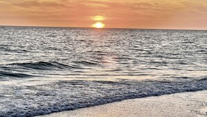 Tramonto sull'oceano con le onde che si infrangono sulla riva.