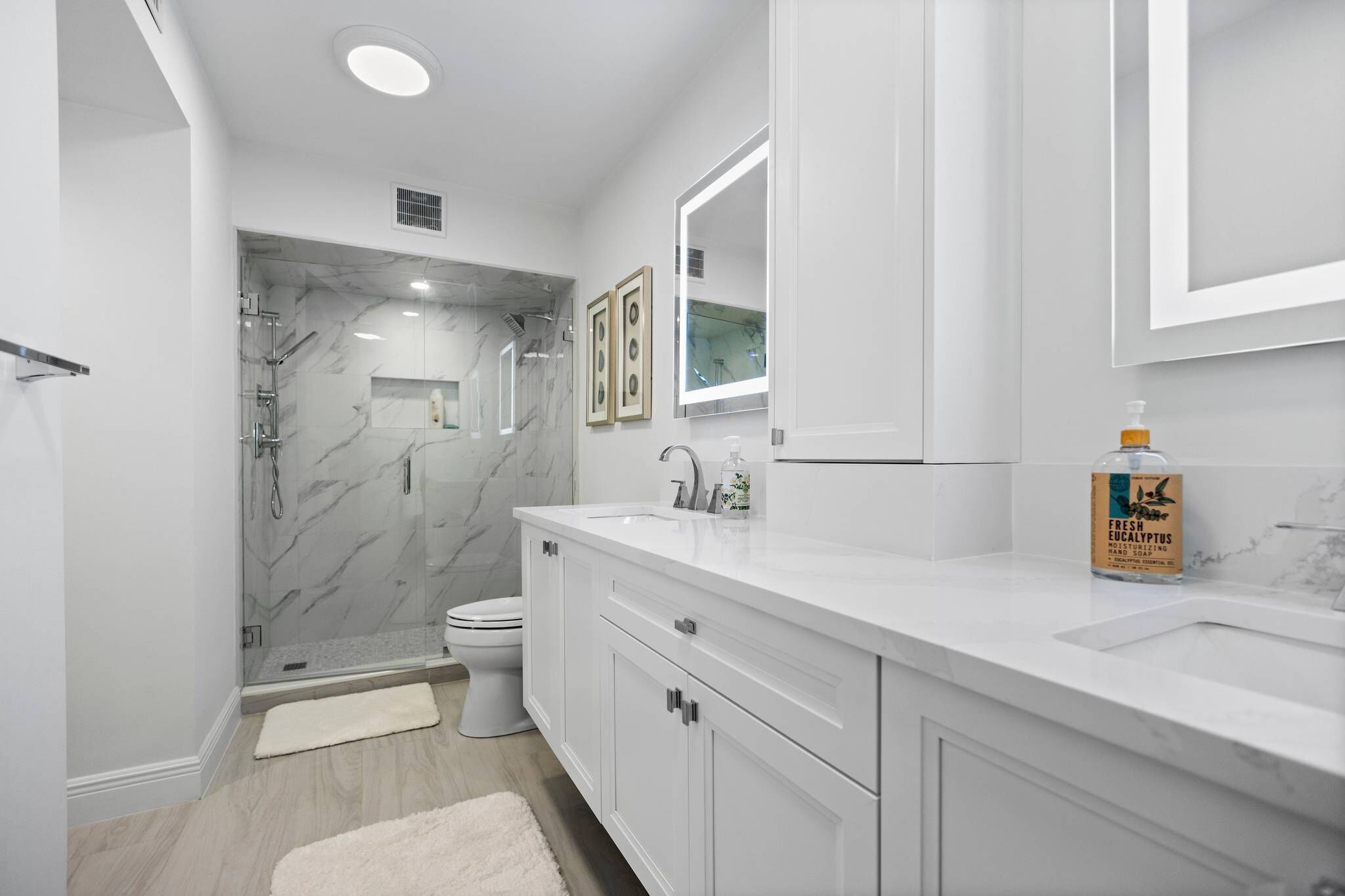 Une salle de bain moderne avec une douche à parois de verre, un lavabo blanc et un grand miroir.