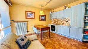 Un espace de vie compact comprenant un coin repas, une kitchenette et un canapé avec des coussins.