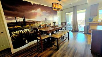 A dining area with a mural of a desert landscape, wooden furniture, and a hanging light fixture.