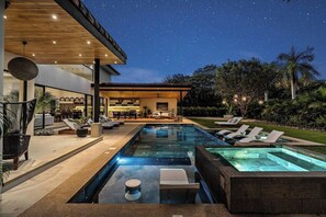 A modern outdoor pool area with lounge chairs and a covered seating area. - Casa Ola Aloha (Tamarindo)