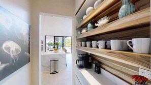 A modern kitchen with a coffee machine, a trash bin, and a view of the outdoors. - Casa Ola Aloha (Tamarindo)