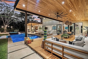 A modern outdoor living area with a pool, wooden deck, and comfortable seating.