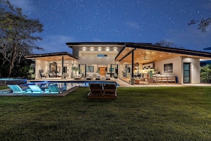 A modern house with a swimming pool, outdoor seating, and a covered patio.