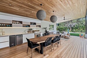 A modern kitchen with a wooden ceiling, built-in appliances, and a dining area with a large table and chairs. - Casa Ola Aloha (Tamarindo)