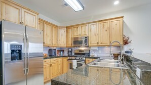 A modern kitchen with wooden cabinets, stainless steel appliances, granite countertops, and a built-in oven. - Winter Park Condo w/ Balcony & Mtn Views! (Winter Park)