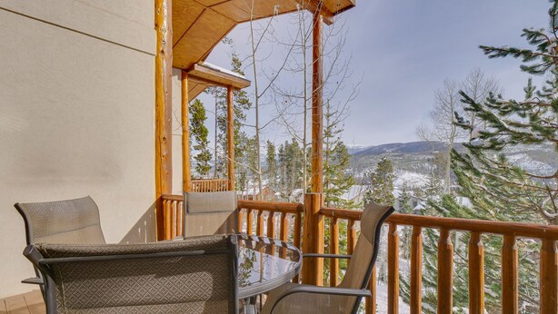 A wooden deck with outdoor furniture, a wooden railing, and a view of snow-covered trees and mountains. - Winter Park Condo w/ Balcony & Mtn Views! (Winter Park)