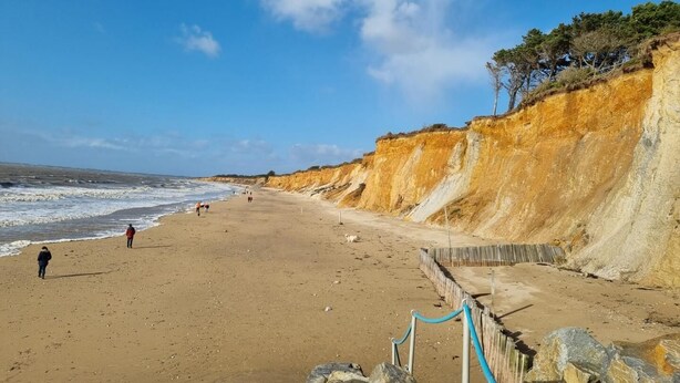 A beach with a sandy shore, a wooden fence, and a cliff with sparse vegetation. - La Maison de Louise - Ferel (FEREL)
