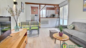 A cozy living room with a sofa, a wooden coffee table, and a dining area with chairs and a table. - La Maison de Louise - Ferel (FEREL)