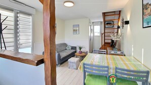 A cozy living area with a sofa, a dining table with chairs, and a bookshelf. - La Maison de Louise - Ferel (FEREL)